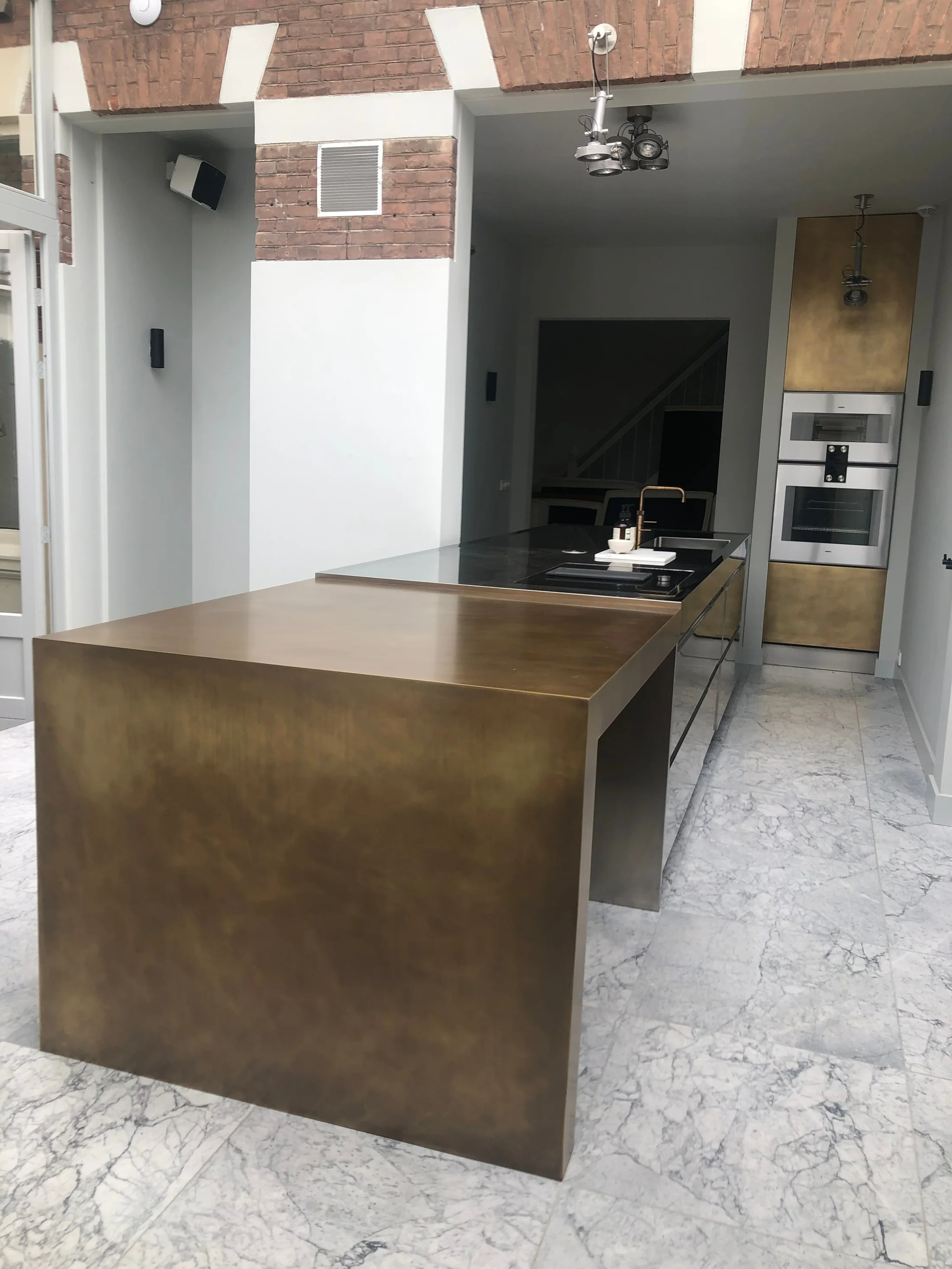Keukeneiland en hoge kast in warme metaaltinten