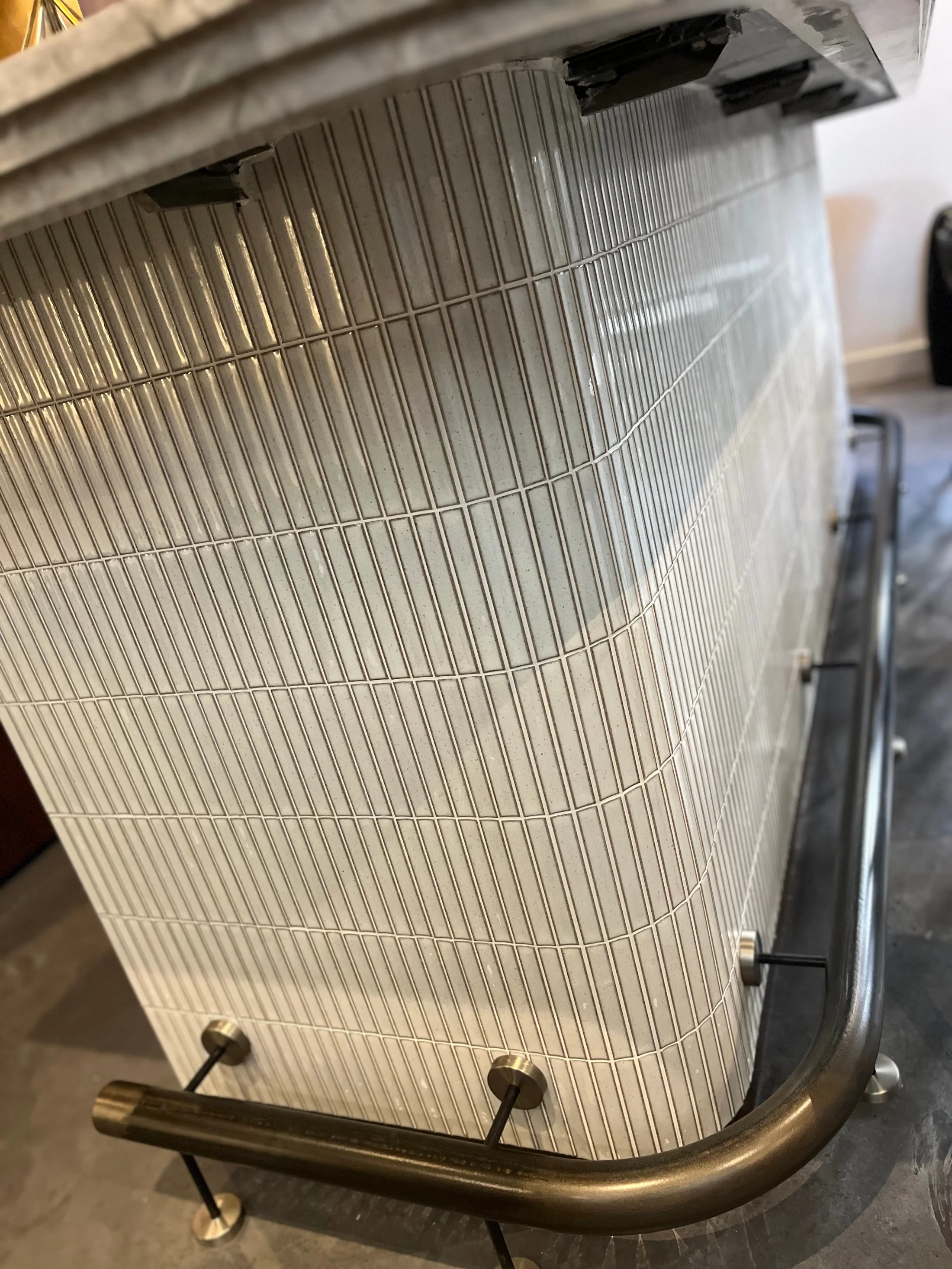 Detail van de verticale tegels en voetsteun van de bar